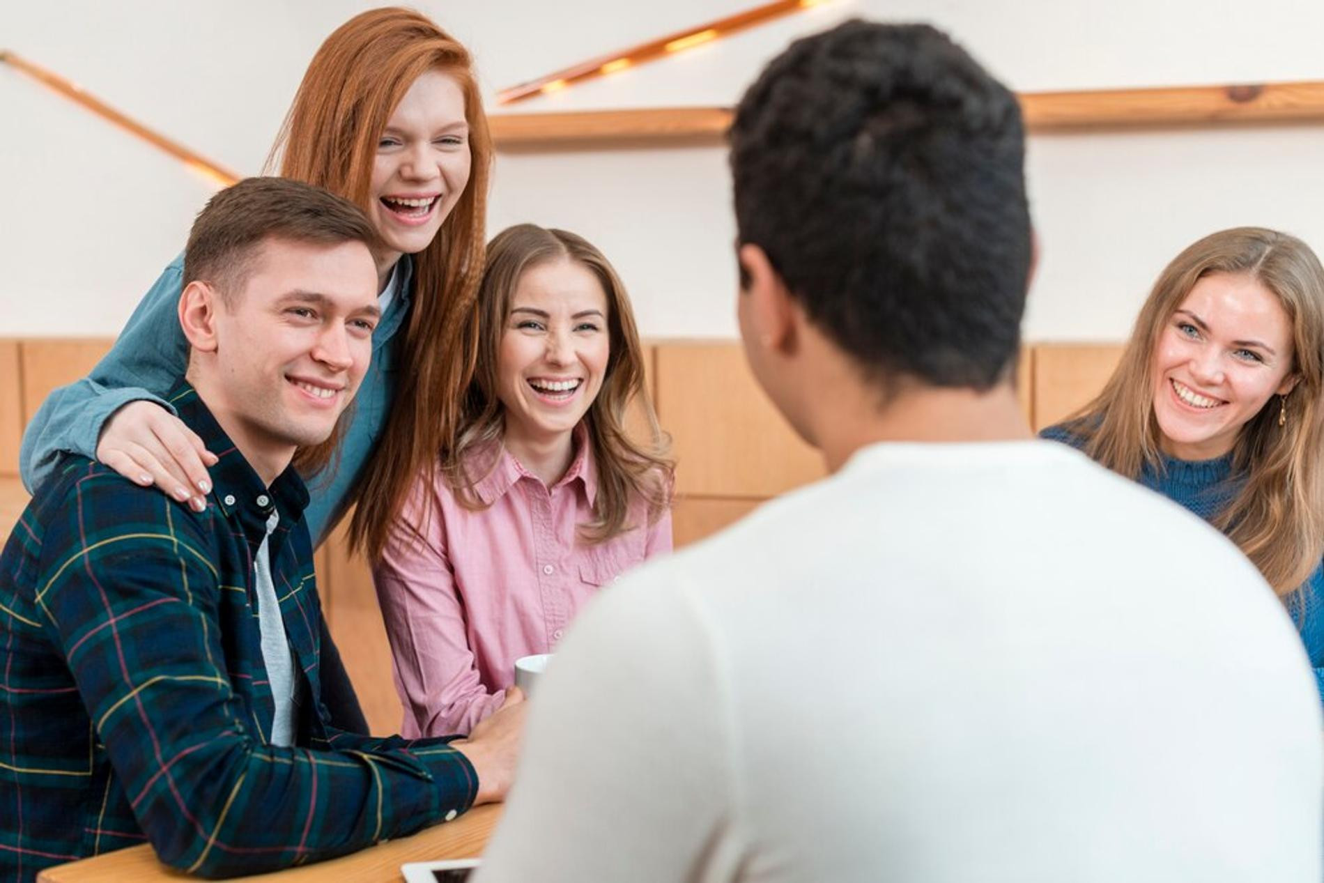 Друзья и встречи. Веселая компания друзей. Разговор с иностранцем. Человек сидит за столом. Подросток сидит в телефоне.